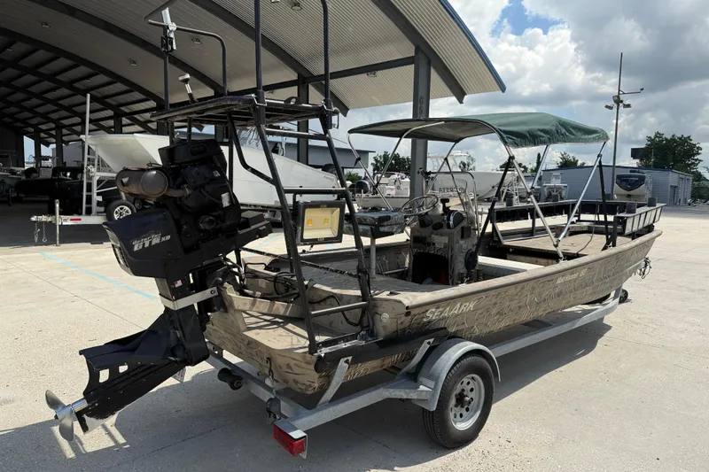 Slide: The Image of 2016 SeaArk 180 Mudrunner boat on trailer, featuring camouflage design and canopy. - 6