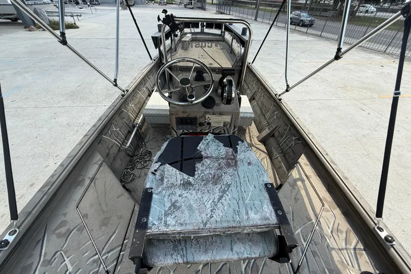 Slide: The Image of 2016 SeaArk 180 Mudrunner boat interior with steering wheel and controls, parked on concrete. - 7