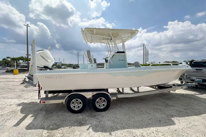 Slide: The Image of 2025 Ranger 2360 Bay boat on trailer under cloudy sky. - 2