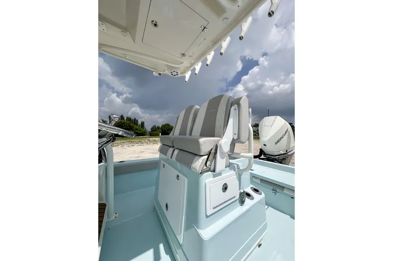 Slide: The Image of 2025 Ranger 2360 Bay boat interior with seating and Mercury engine, under cloudy sky. - 9