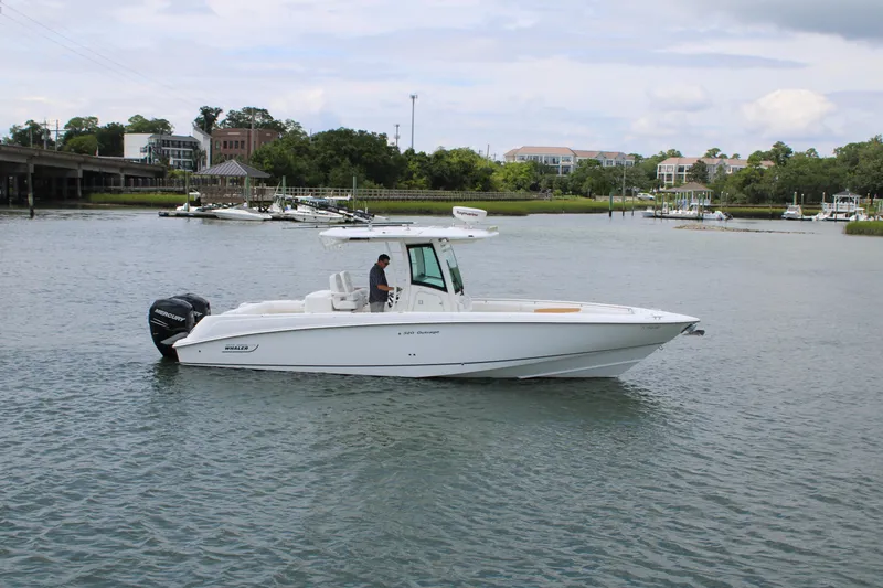 Slide: The Image of 2015 Boston Whaler 320 Outrage boat cruising on a calm river near a marina. - 1