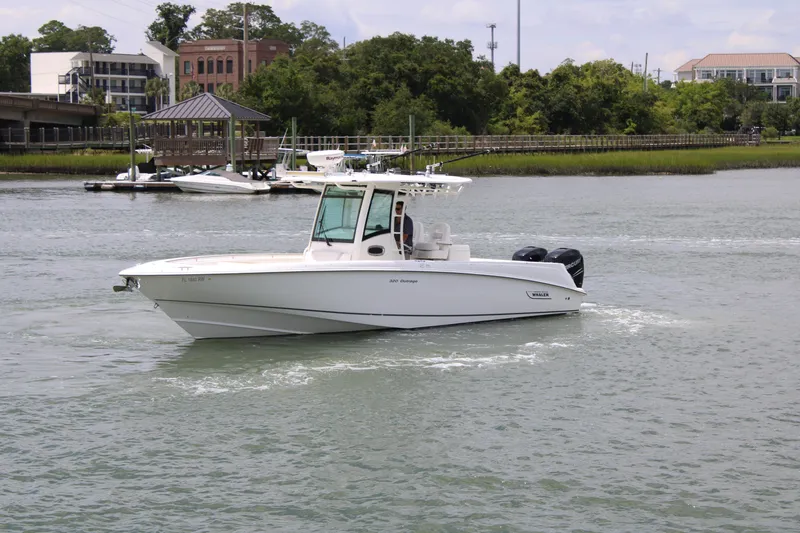 Slide: The Image of 2015 Boston Whaler 320 Outrage boat cruising on a calm river near a marina. - 10