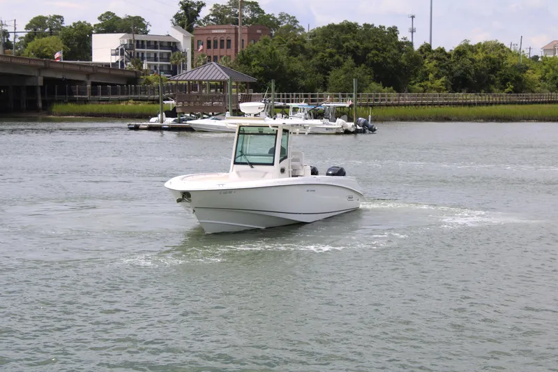 Slide: The Image of 2015 Boston Whaler 320 Outrage boat cruising on a calm river near a marina. - 11
