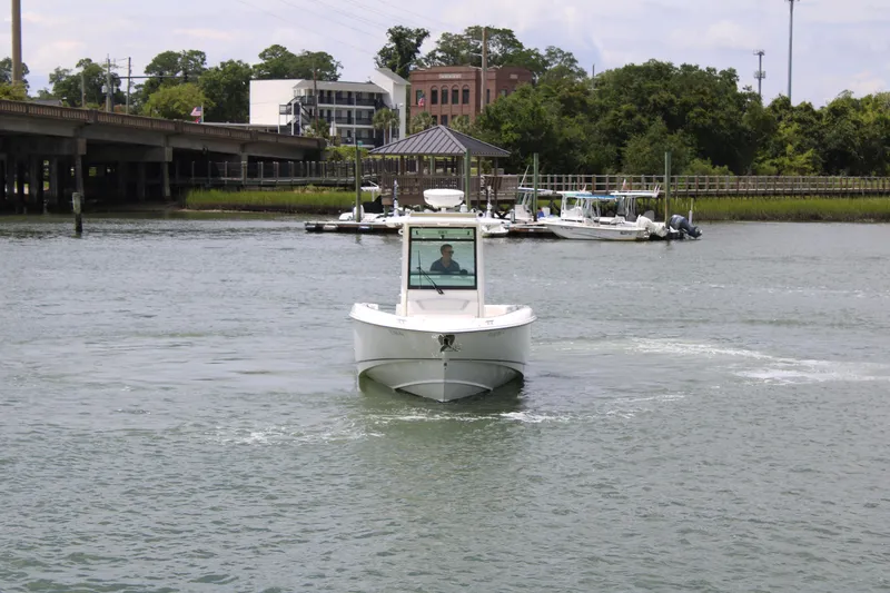 Slide: The Image of 2015 Boston Whaler 320 Outrage boat navigating a calm waterway near a dock. - 12