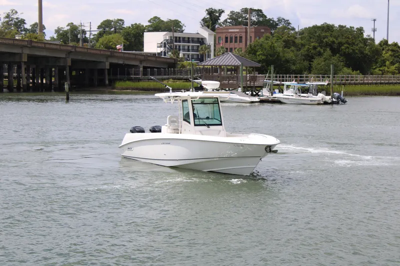 Slide: The Image of 2015 Boston Whaler 320 Outrage boat cruising near a dock with lush greenery. - 13