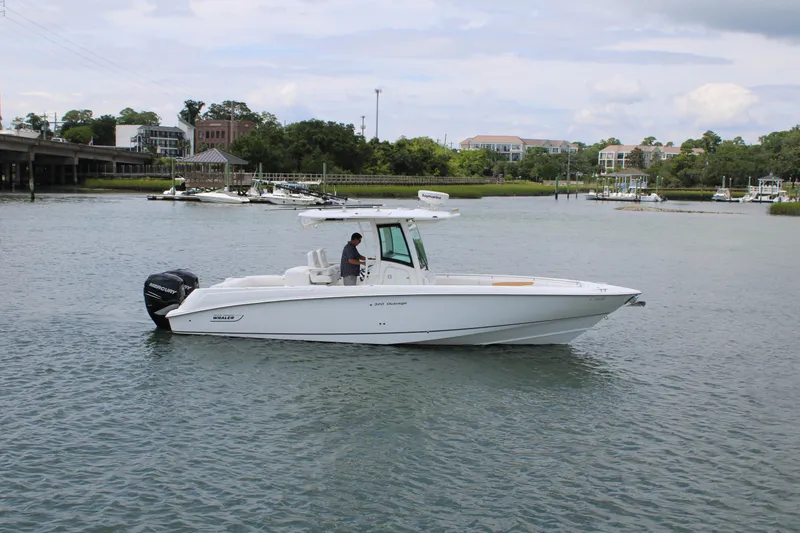 Slide: The Image of 2015 Boston Whaler 320 Outrage boat on calm water near a marina. - 2