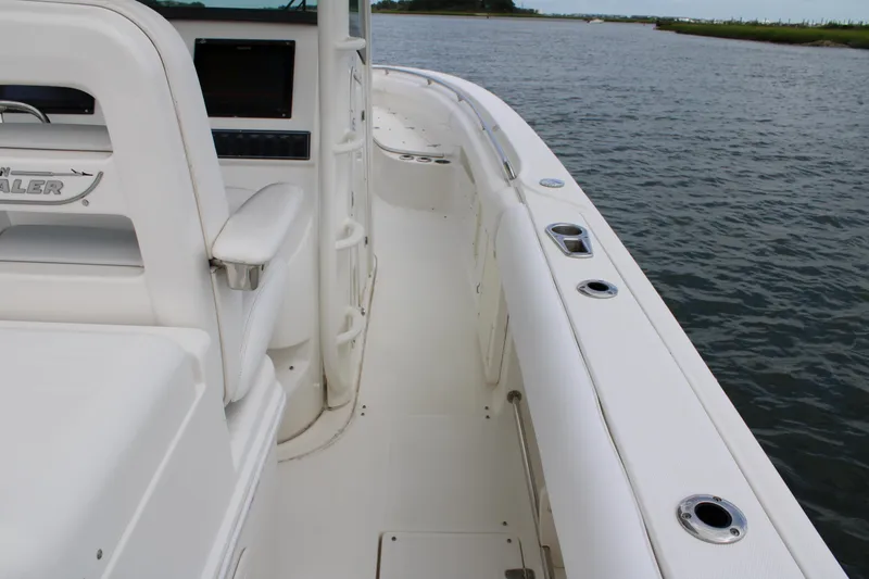 Slide: The Image of 2015 Boston Whaler 320 Outrage boat interior, featuring white seating and console by the water. - 28