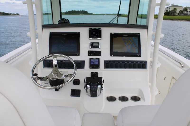 Slide: The Image of 2015 Boston Whaler 320 Outrage helm with dual displays and steering wheel on water. - 32