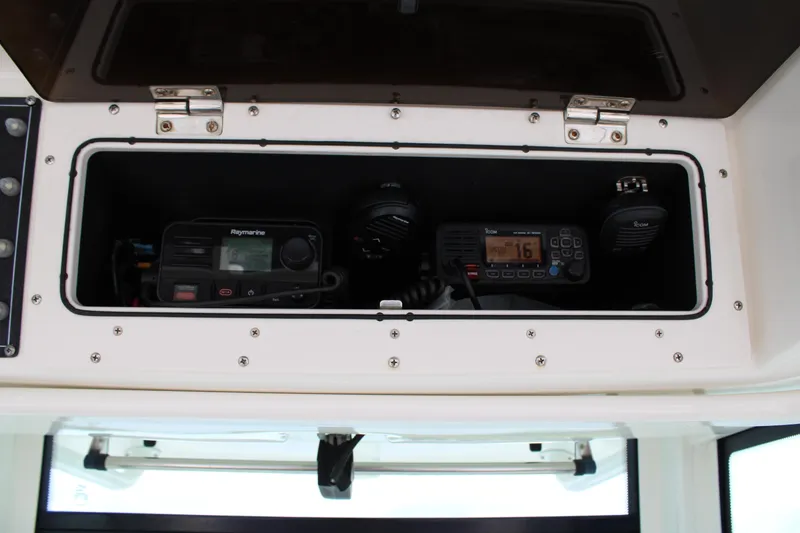 Slide: The Image of 2015 Boston Whaler 320 Outrage electronics compartment with Raymarine and Icom devices. - 36