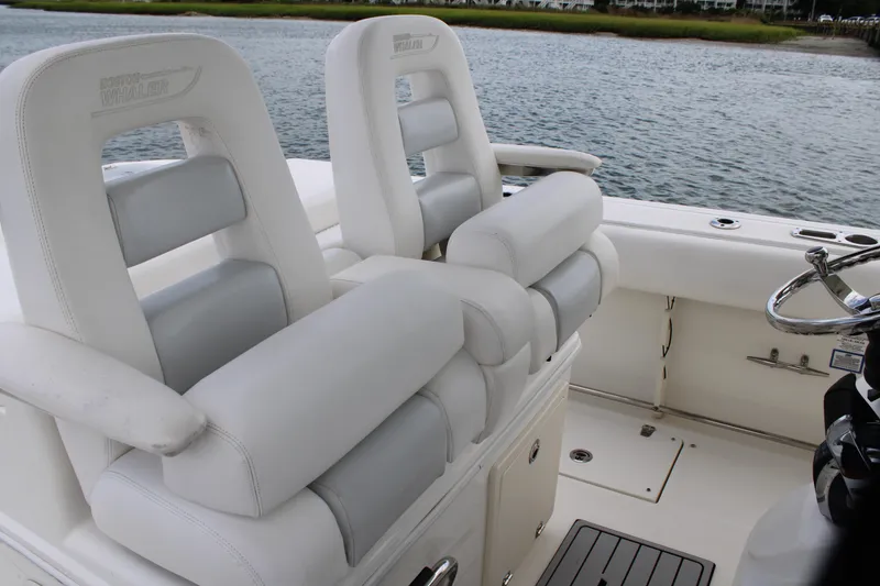 Slide: The Image of 2015 Boston Whaler 320 Outrage boat interior with white cushioned seats and steering wheel. - 44