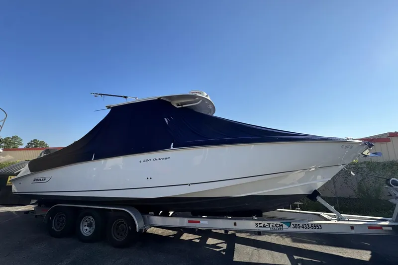 Slide: The Image of 2015 Boston Whaler 320 Outrage boat on trailer, covered, under clear blue sky. - 71
