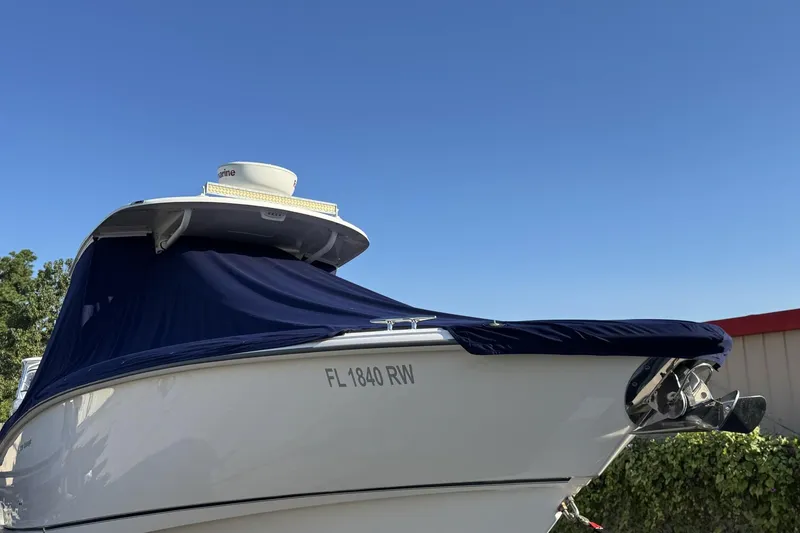 Slide: The Image of 2015 Boston Whaler 320 Outrage boat with blue cover, docked under clear sky. - 73