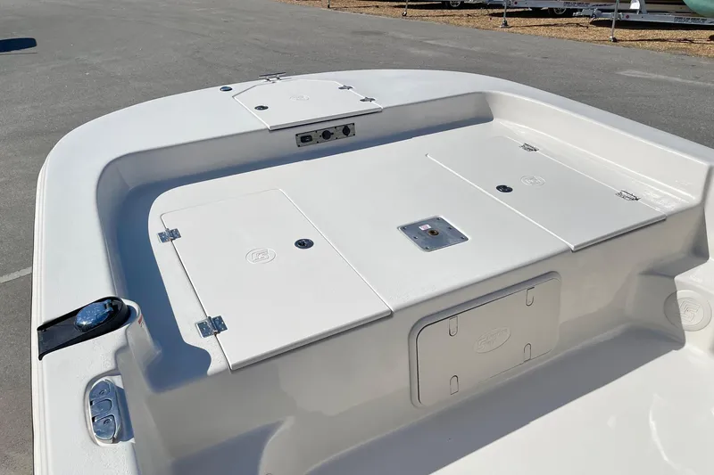 Slide: The Image of 2026 Carolina Skiff 21 LS boat deck with storage compartments, shown in a parking area. - 12