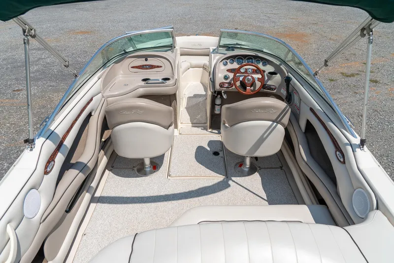 Slide: The Image of 2002 Sea Ray 230 Bow Rider interior with beige seating and wooden steering wheel. - 12