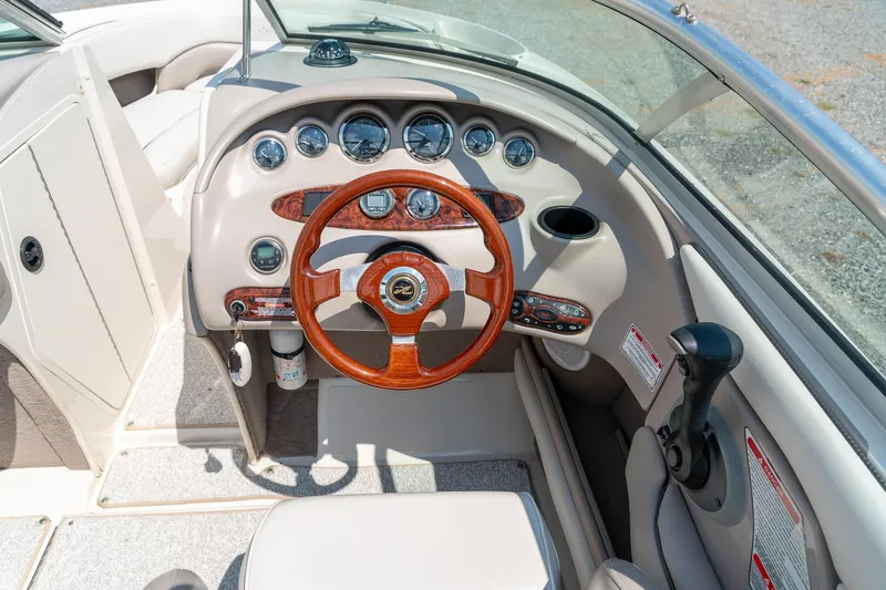 Slide: The Image of 2002 Sea Ray 230 Bow Rider dashboard with wood-accented steering wheel and instrument panel. - 16