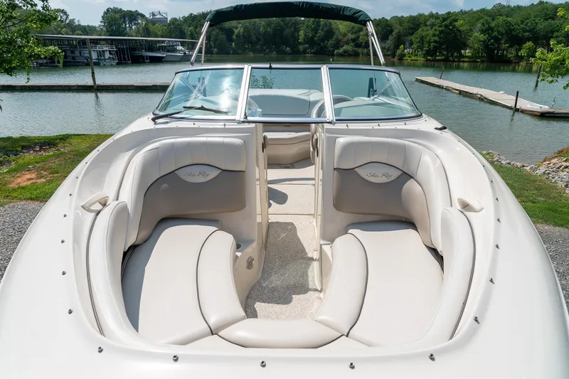 Slide: The Image of 2002 Sea Ray 230 Bow Rider boat with spacious seating, docked by a serene lake. - 20