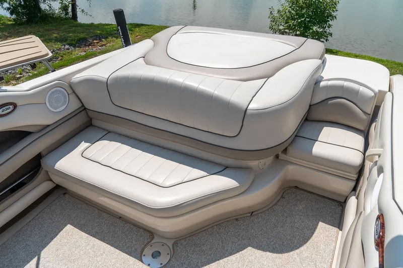 Slide: The Image of 2002 Sea Ray 230 Bow Rider interior with beige seating and lake view. - 26