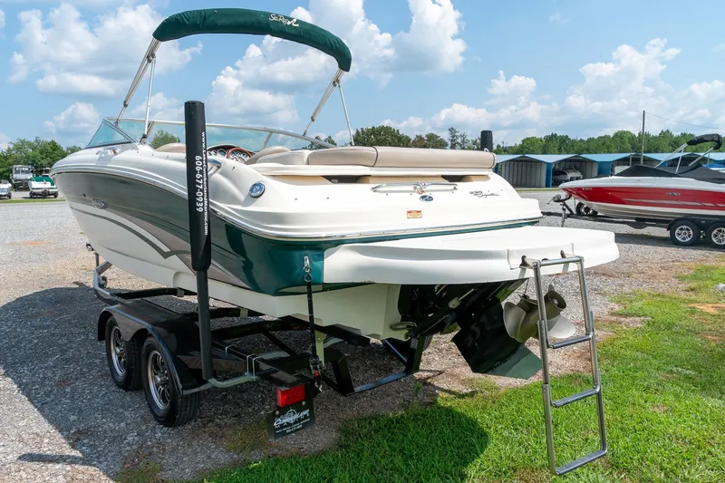 Slide: The Image of 2002 Sea Ray 230 Bow Rider on trailer, green and white, sunny day, outdoor display. - 7