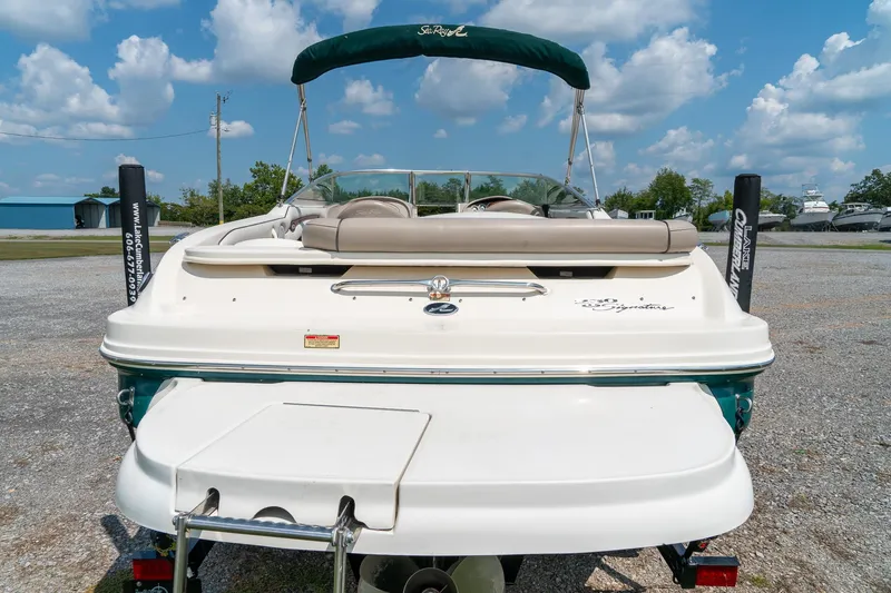 Slide: The Image of 2002 Sea Ray 230 Bow Rider boat, rear view, parked outdoors under a blue sky. - 9