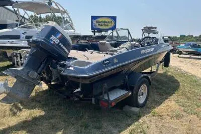 Slide: The Image of 1998 ProCraft 180 Combo boat with outboard motor, parked on a trailer at a marina. - 4