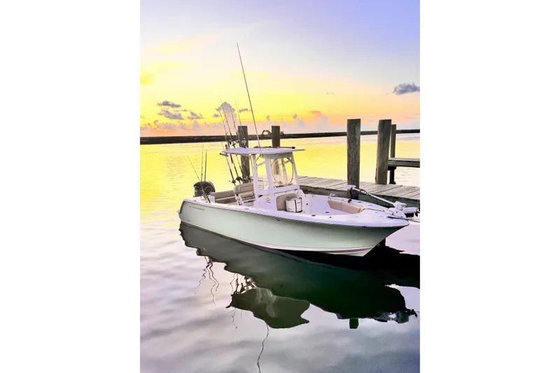 Slide: The Image of 2019 Sportsman Open 232 Center Console boat docked at sunset, calm water reflection. - 20