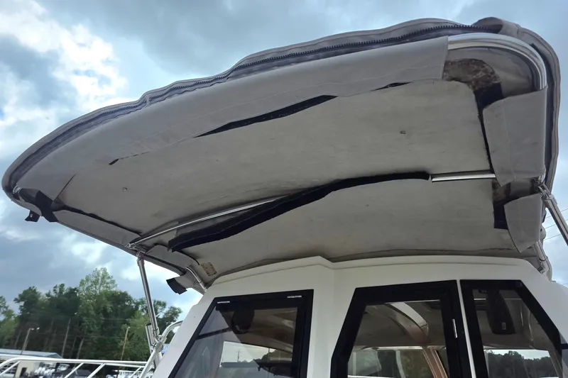 Slide: The Image of 2020 Cutwater C-24 boat with a partially open canvas roof under cloudy sky. - 13