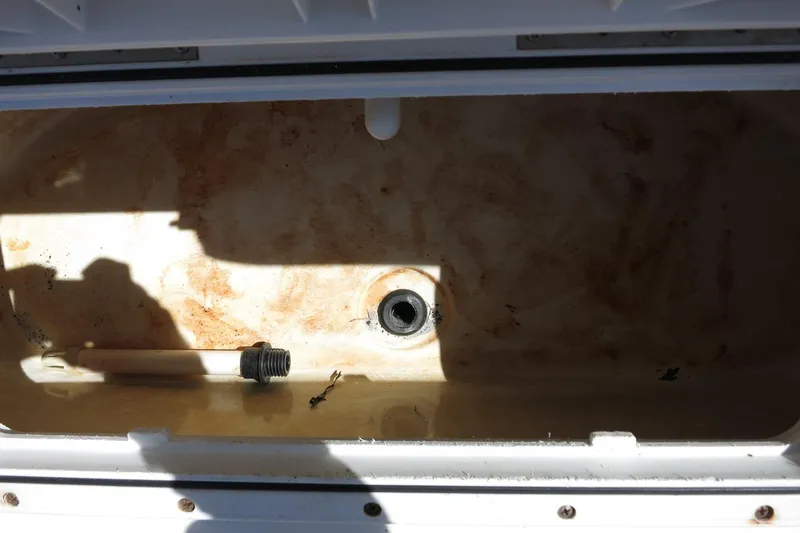 Slide: The Image of Open storage compartment in 2015 NauticStar 203SC Sport Deck boat, showing drain and pipe. - 20