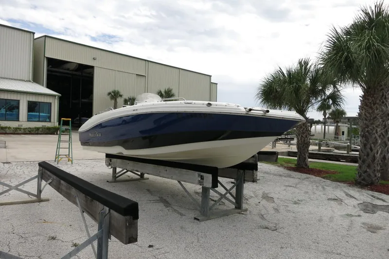 Slide: The Image of 2015 NauticStar 203SC Sport Deck boat on display near palm trees and industrial building. - 41