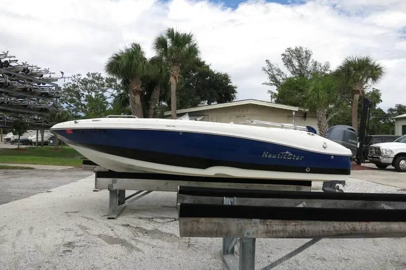 Slide: The Image of 2015 NauticStar 203SC Sport Deck boat on trailer, parked outdoors with palm trees. - 44