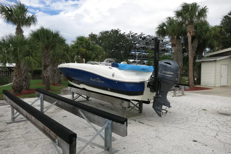Slide: The Image of 2015 NauticStar 203SC Sport Deck boat on trailer, surrounded by palm trees. - 45