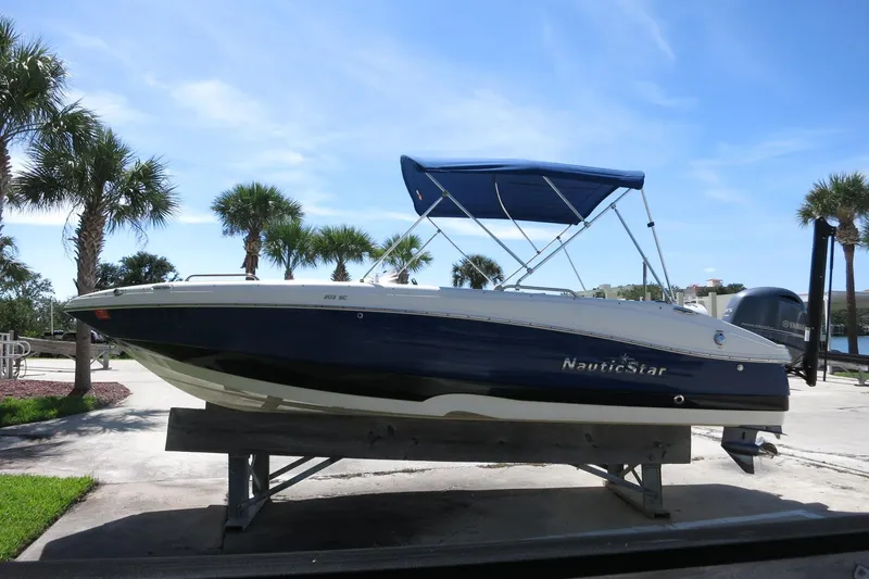 Slide: The Image of 2015 NauticStar 203SC Sport Deck boat on display with blue canopy, surrounded by palm trees. - 9
