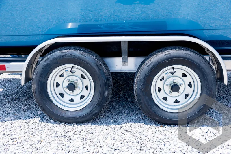 Slide: The Image of 2026 Tidewater 2110 Bay Max trailer wheels on gravel surface. - 15