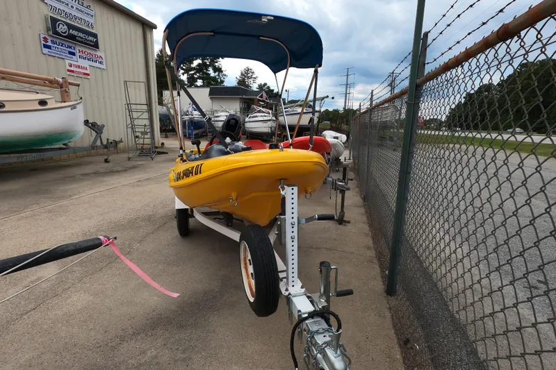 Slide: The Image of Yellow 2022 River Boats 290XR on trailer, parked near a fence at a marina. - 4