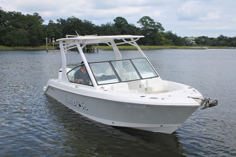 Slide: The Image of 2020 Edgewater 230 CX boat on calm water with lush green shoreline. - 11