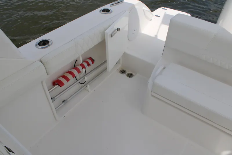Slide: The Image of 2020 Edgewater 230 CX boat interior with white seating and storage compartment. - 20