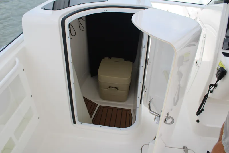 Slide: The Image of 2020 Edgewater 230 CX boat interior with open compartment and portable toilet. - 35