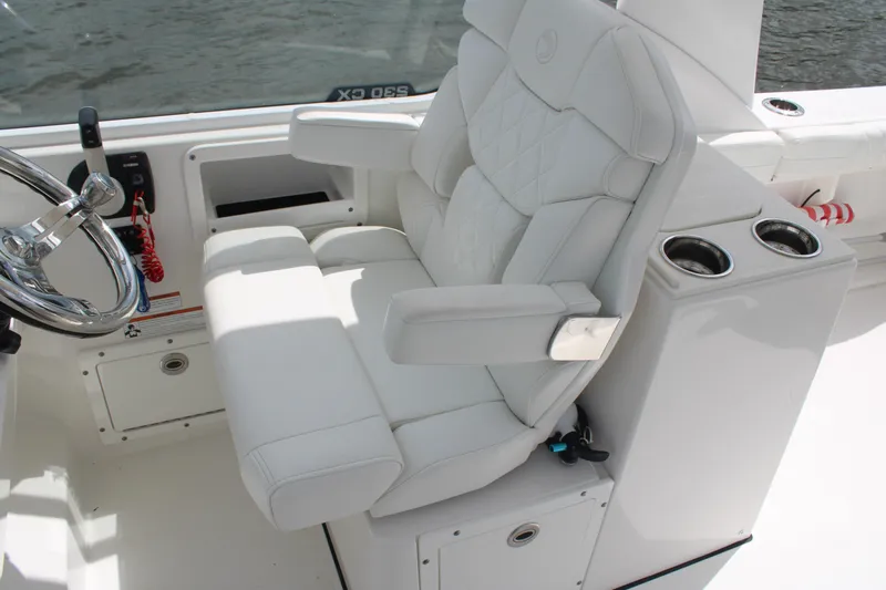 Slide: The Image of Luxurious white captain's chair on 2020 Edgewater 230 CX boat, featuring cup holders and steering wheel. - 37