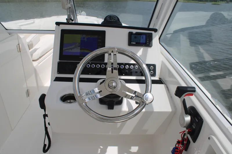 Slide: The Image of Edgewater 230 CX 2020 boat helm with steering wheel and navigation controls. - 38