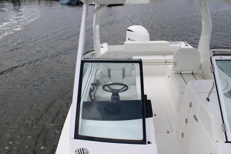 Slide: The Image of 2020 Edgewater 230 CX boat interior with steering wheel, white seating, and Yamaha engine. - 52