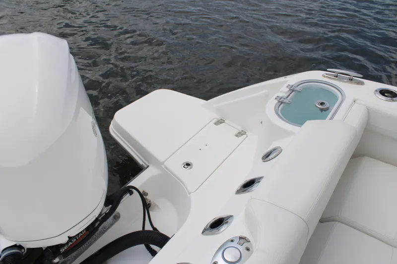 Slide: The Image of 2020 Edgewater 230 CX boat interior with motor and seating, on water. - 56