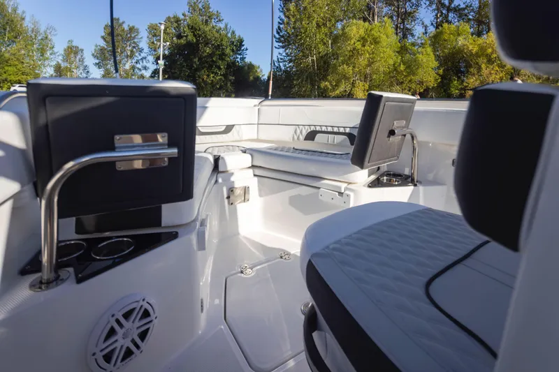 Slide: The Image of 2024 Blackfin 222 CC boat interior with seating and cup holders, surrounded by trees. - 18