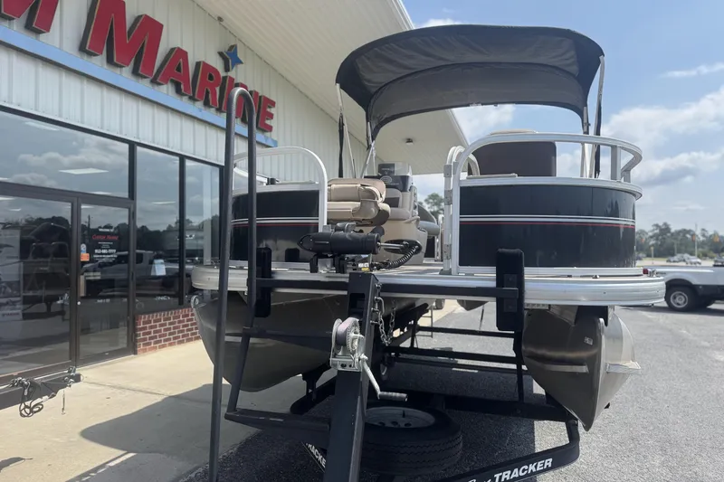 Slide: The Image of 2017 Sun Tracker Bass Buggy 18 DLX pontoon boat on trailer outside marine store. - 14