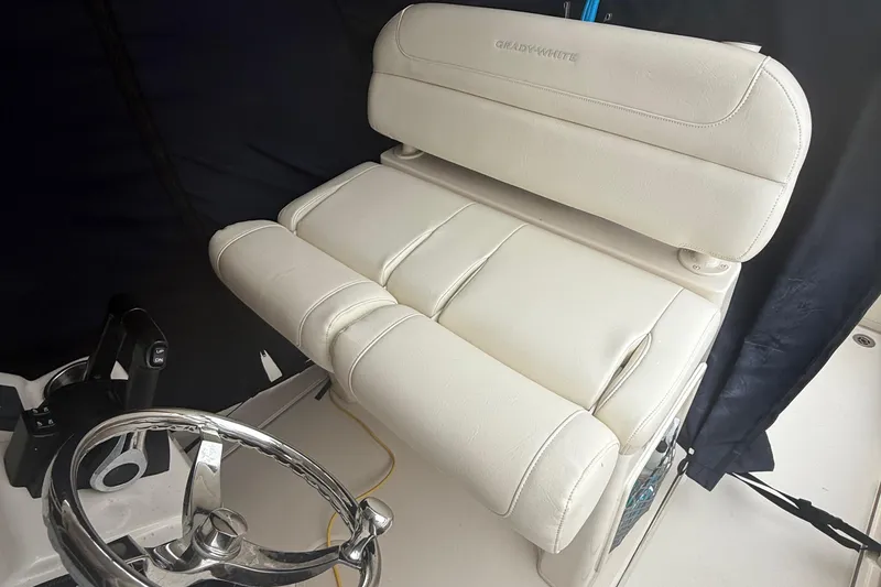 Slide: The Image of 2020 Grady-White Fisherman 257 boat seat and steering wheel, featuring white upholstery. - 26