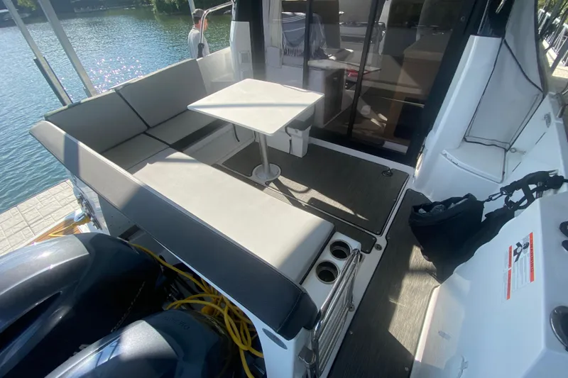 Slide: The Image of 2024 Jeanneau NC 895 boat deck with seating and table, docked by the water. - 11