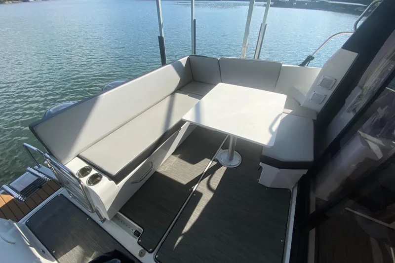 Slide: The Image of 2024 Jeanneau NC 895 boat interior with seating and table on calm water. - 12