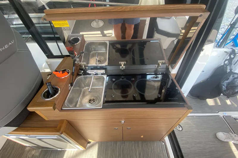 Slide: The Image of 2024 Jeanneau NC 895 boat kitchen with sink, stove, and wooden cabinetry. - 17