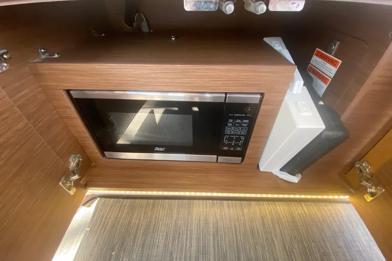 Slide: The Image of 2024 Jeanneau NC 895 interior with built-in microwave and wooden cabinetry. - 19
