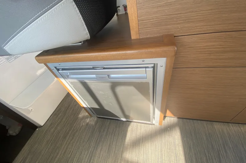 Slide: The Image of 2024 Jeanneau NC 895 interior with compact built-in refrigerator and wooden cabinetry. - 20