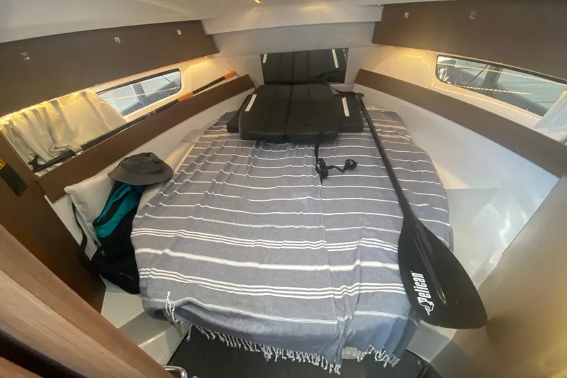 Slide: The Image of 2024 Jeanneau NC 895 cabin interior with striped bedding and paddle. - 35