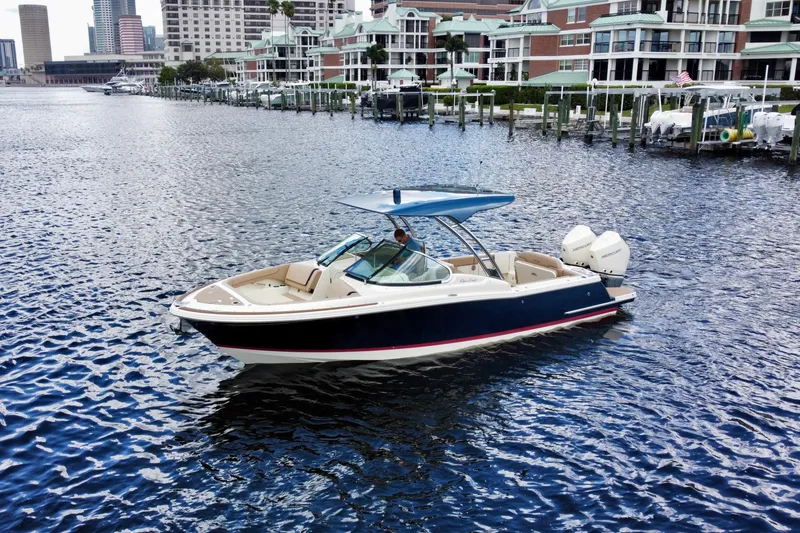 Slide: The Image of 2023 Chris-Craft Calypso 28 boat cruising in a marina with waterfront buildings. - 3